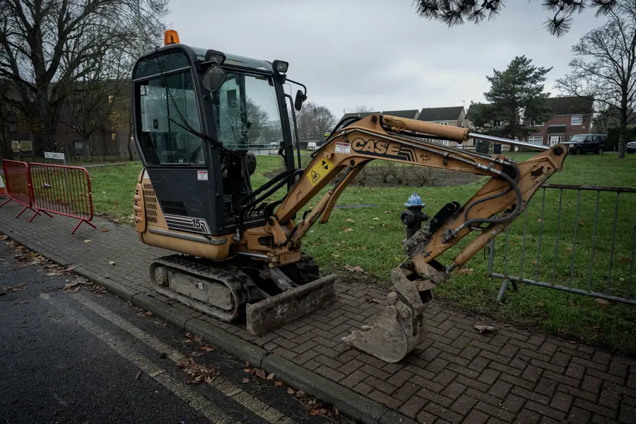 Mini excavator digging a trench beside a footpath