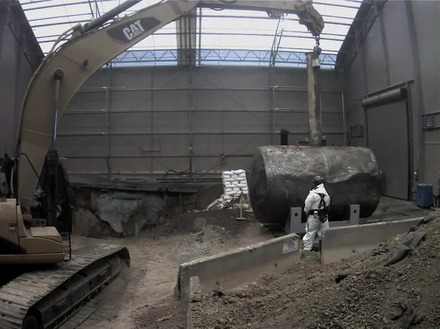 Excavator removing contaminated material inside a temporary enclosure